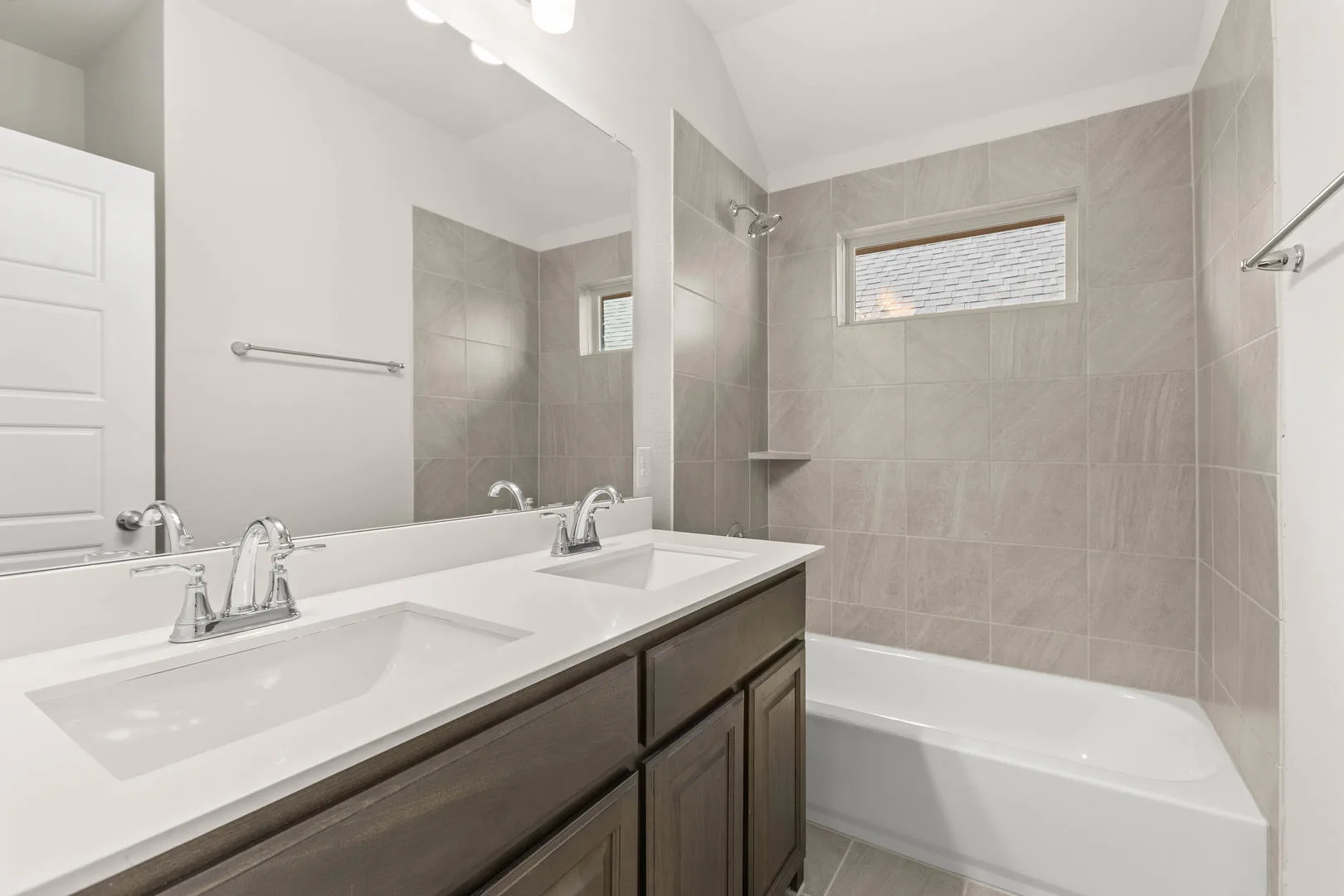Secondary bathroom with dual vanity and shower/tub combo in a new traditional style home by Kindred Homes