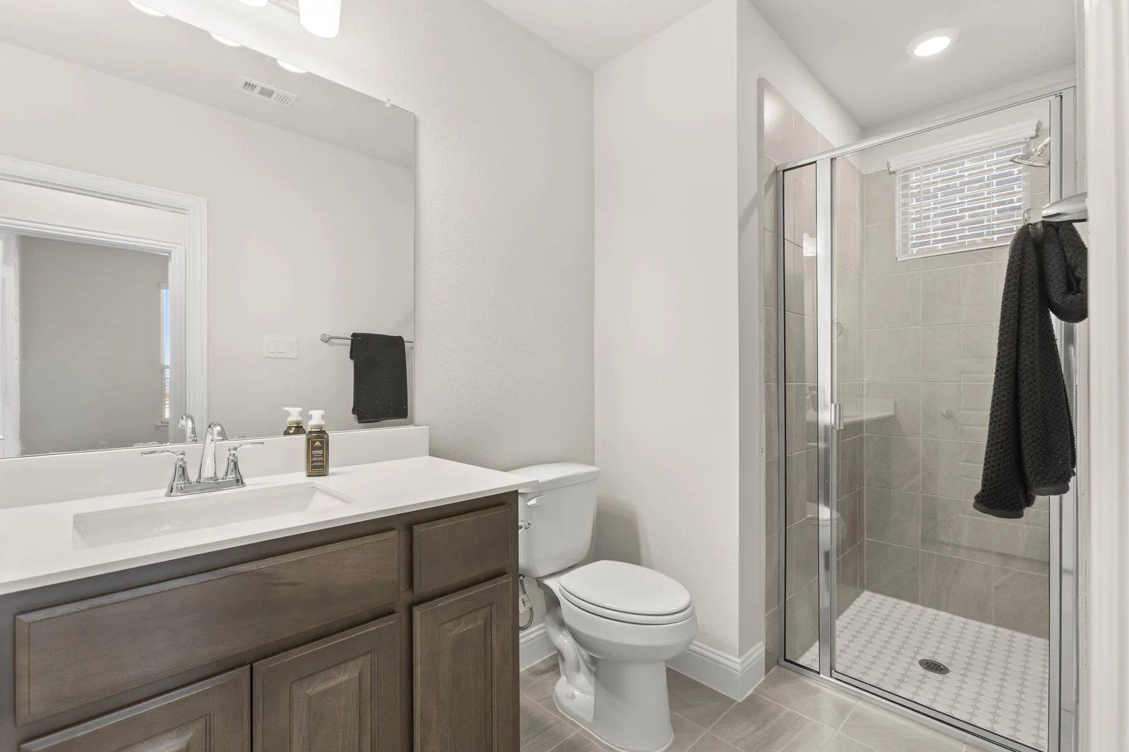 Secondary bathroom with walk-in shower in a new traditional style home by Kindred Homes